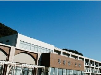 青い空の下には横に長い建物が建っている。大きくホーム名が書かれていて、横に長いデザインでベランダも付いている。