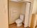壁にL字型に折れ曲がった手すりとトイレットペーパーがあるトイレ