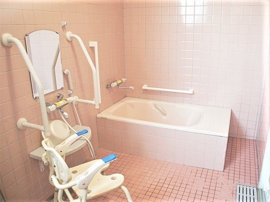 介護用の手すりがついた浴室の様子。シャワーチェアと立ち上がり用の手すりが印象的