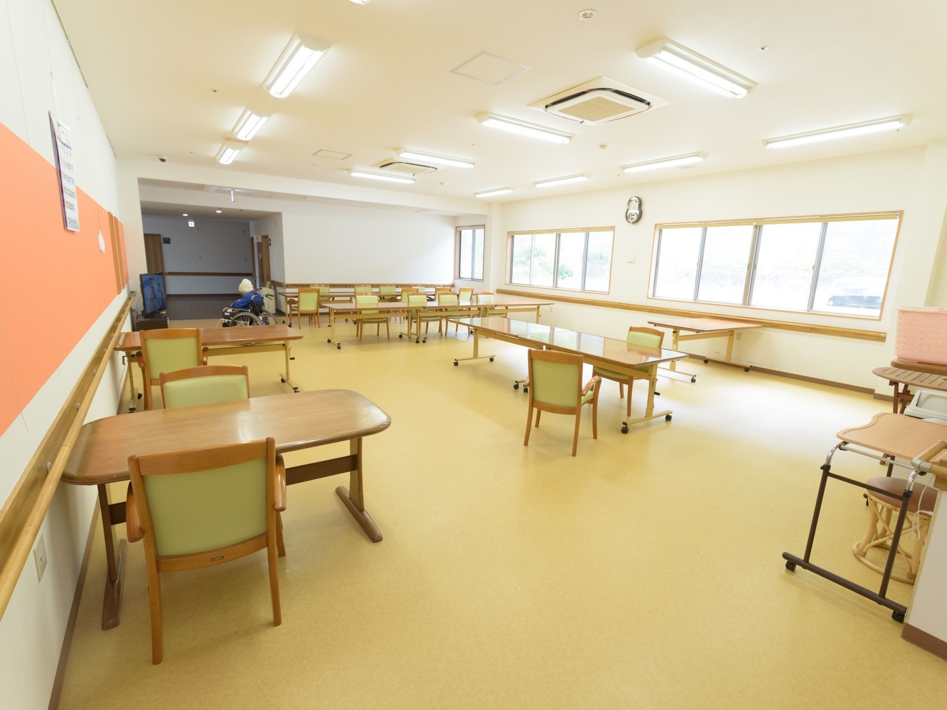 天井にたくさんの蛍光灯が設置され、窓から明るい光が入る広々とした部屋である。ダイニングテーブルや椅子がたくさん置いてある。