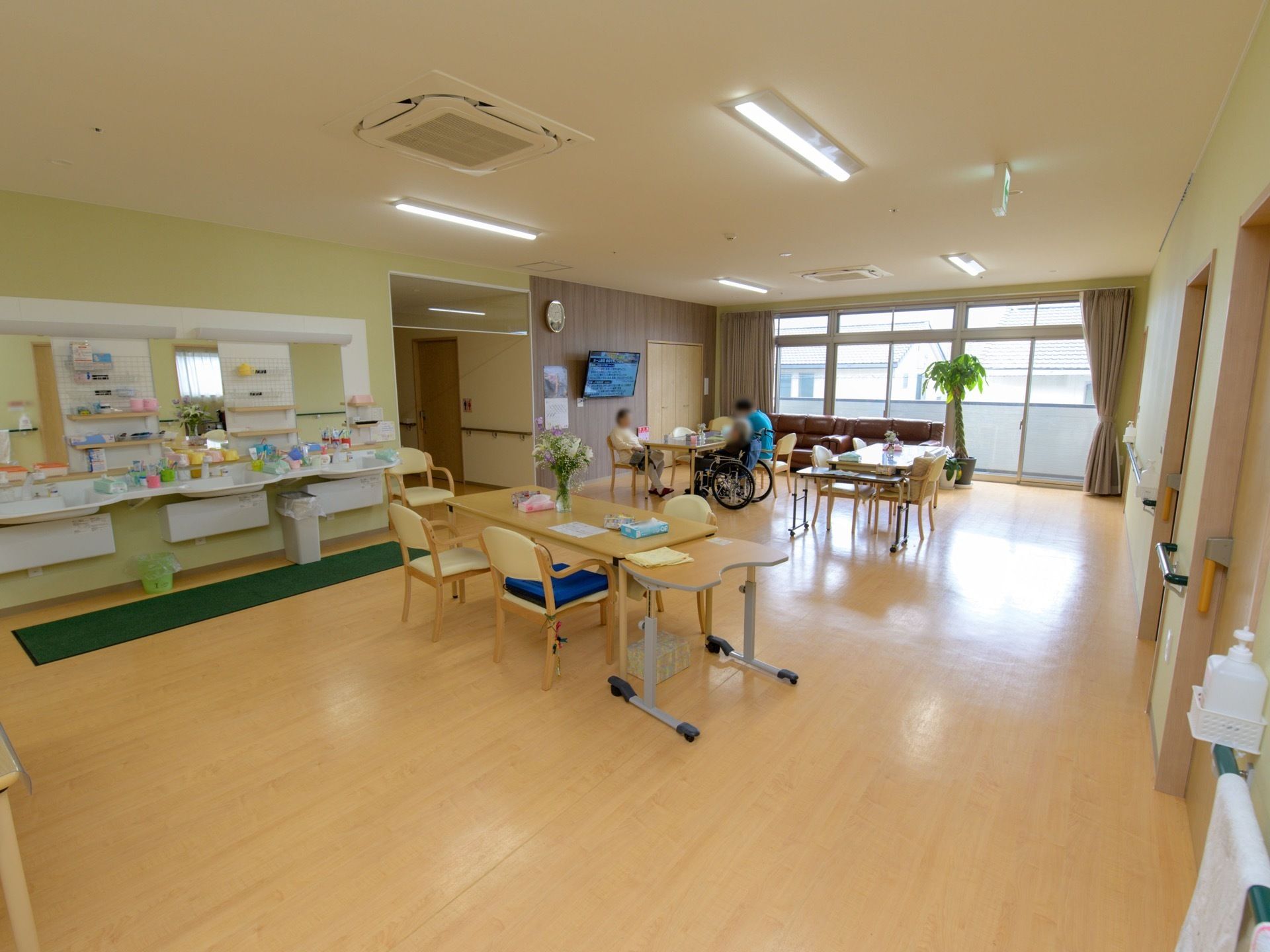 食堂には、大きな鏡がついた洗面台が３つ並んで設置されている。窓際には、ソファと観葉植物の鉢が置かれている。