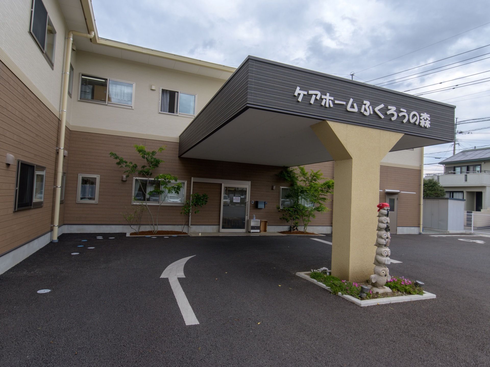 玄関には車寄せがあり、幕板に大きな文字で施設名称が表示されている。車寄せの柱の前に、ふくろうが重なっている石のオブジェがある。