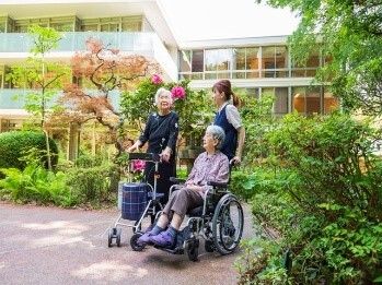 車椅子に座っている高齢女性と手を差し伸べる女性ヘルパー