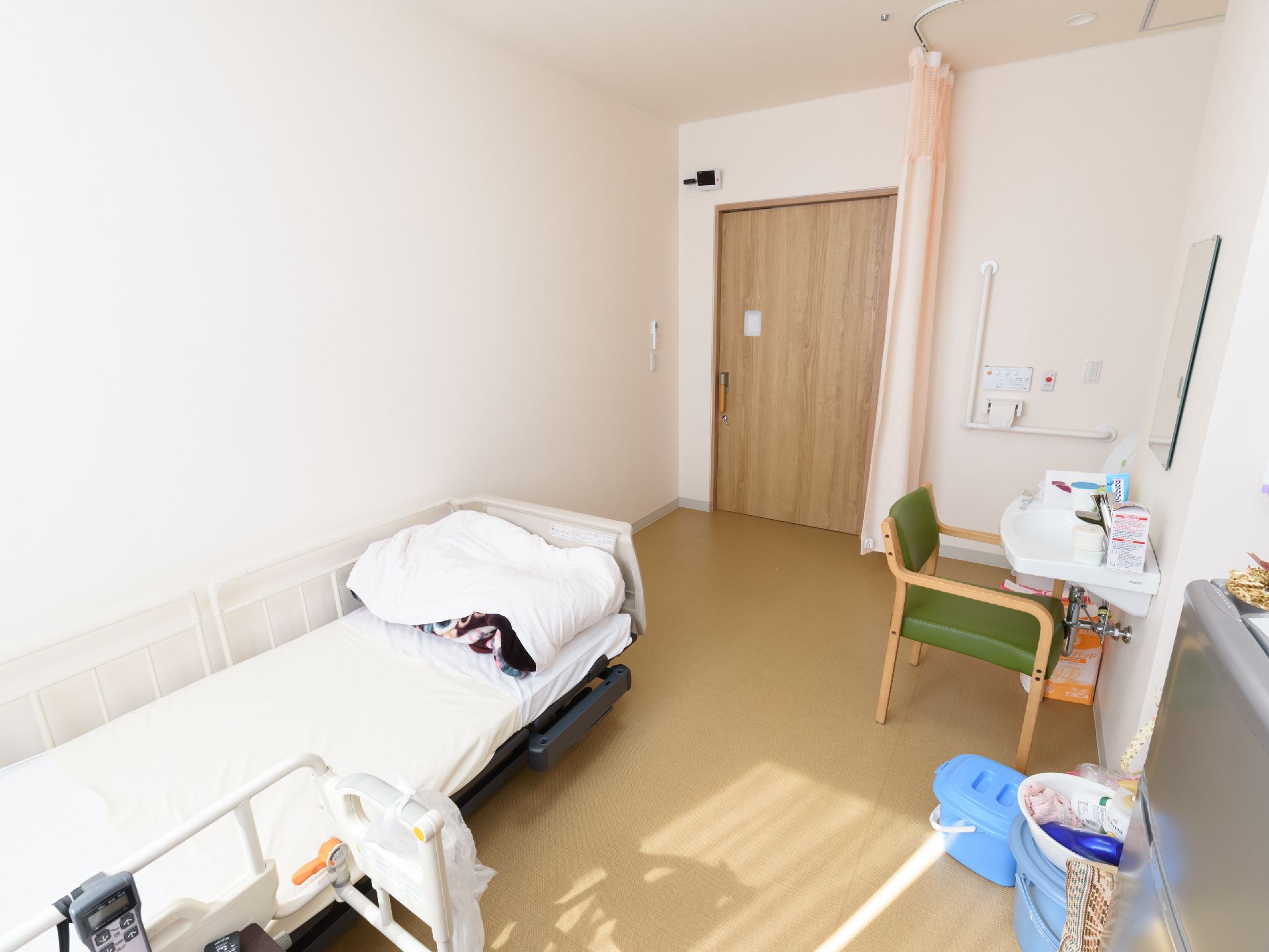 電動介護ベッドや洗面台、トイレが備わっている。トイレの横の壁には緊急コールがあり、洗面台の前の壁には鏡が設置されている。