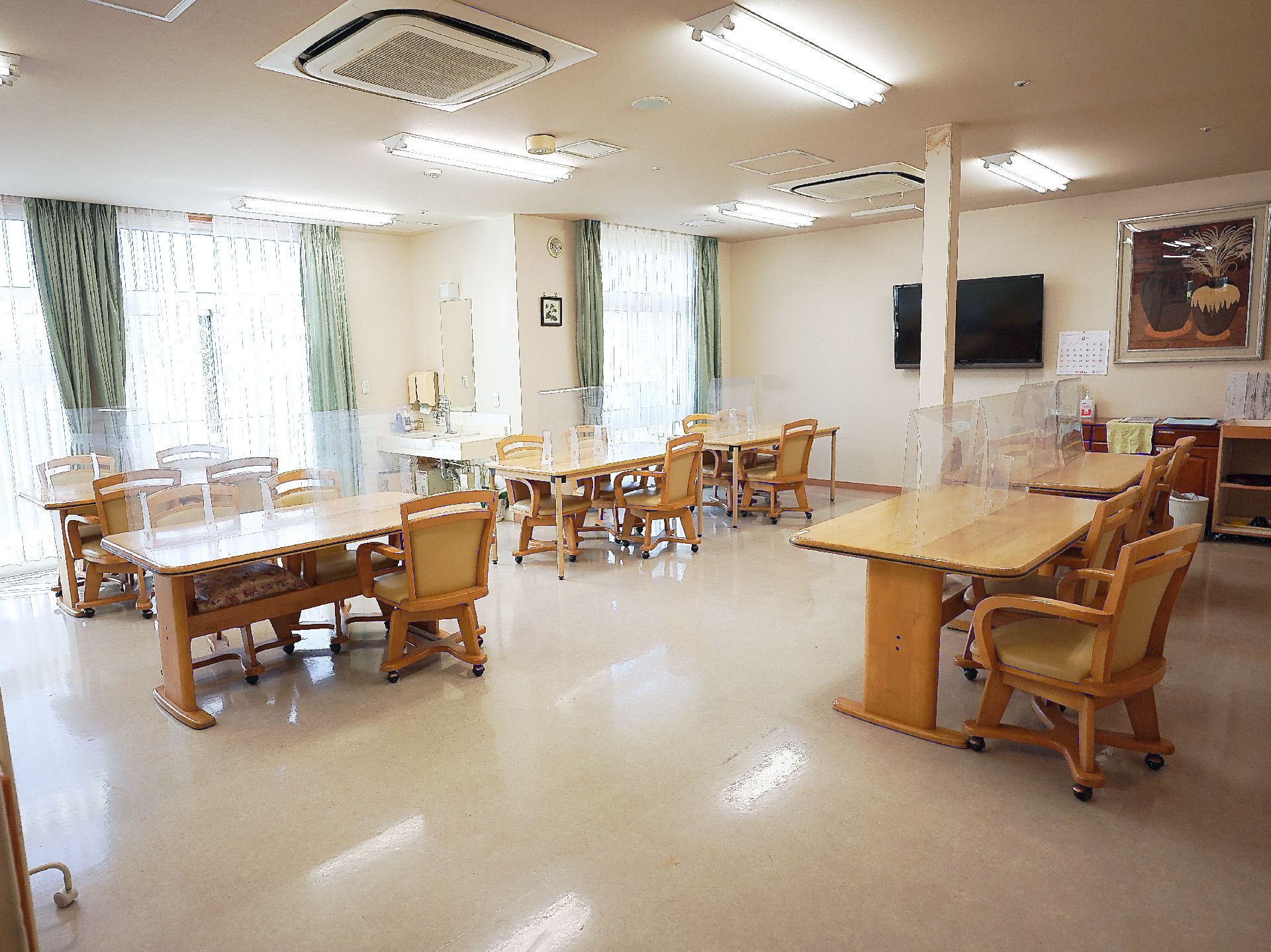 長テーブルと椅子が置かれ、窓から光が入っている共有スペース