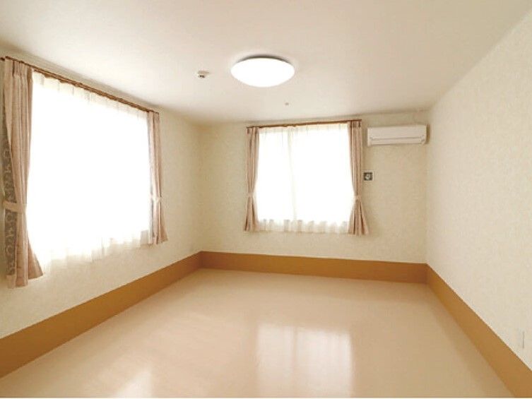 窓の横の天井近くの壁にエアコンが設置されている部屋
