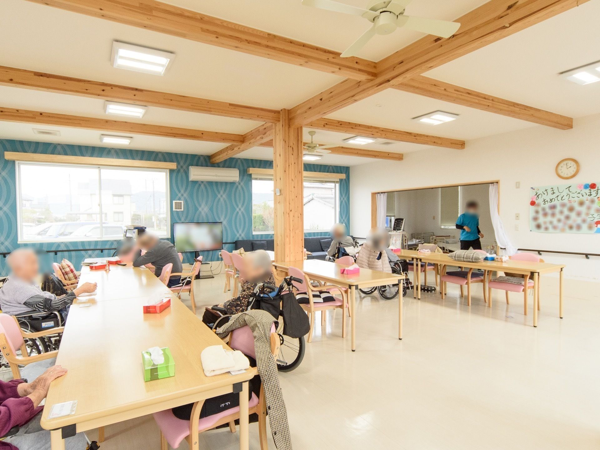 たくさんのテーブルが並ぶ共有スペースで会話を楽しむ入居者様