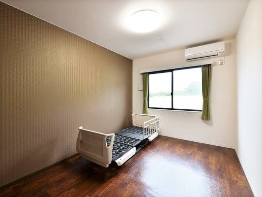 シンプルなワンルームタイプの居室にはベッドとエアコンを完備。窓の外には自然が見える。