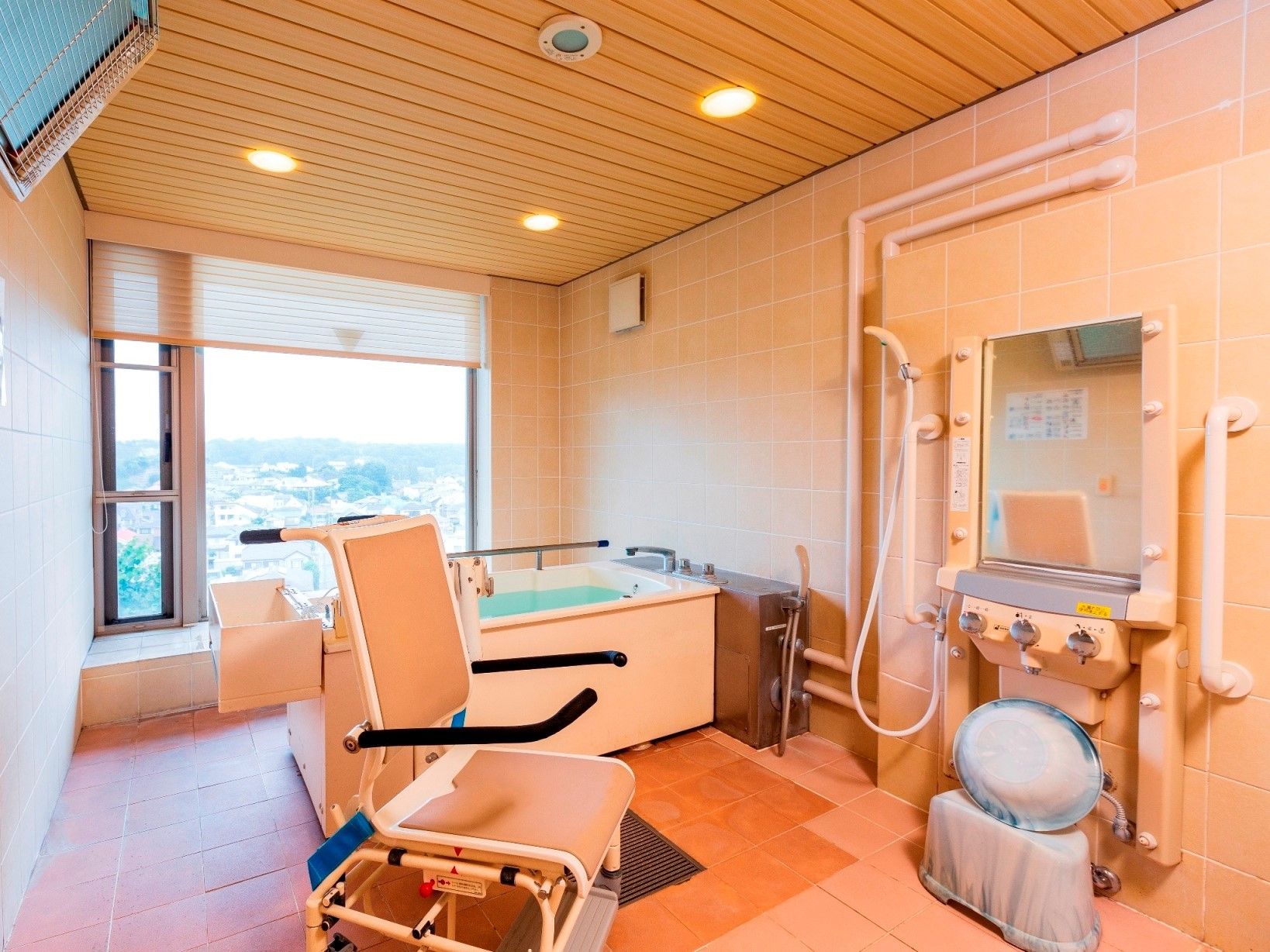 壁面と天井には木材を使用し、洗い場には石材を用いた、温かみのあるモダンなデザインの浴室。手すりもあり安全面にも配慮している。