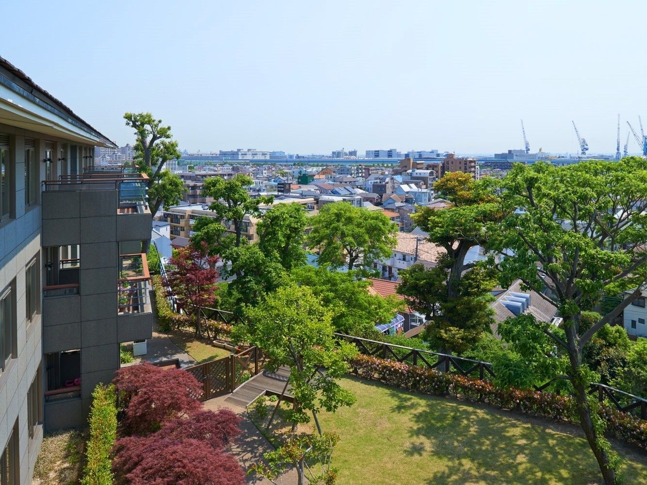 敷地内の緑豊かな木々の背景に広がる高台に立地する施設からの眺望