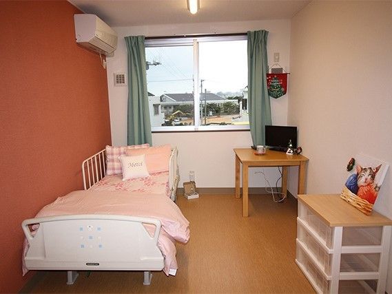 赤い壁紙が印象的な部屋。テレビやタンス類が写っている写真
