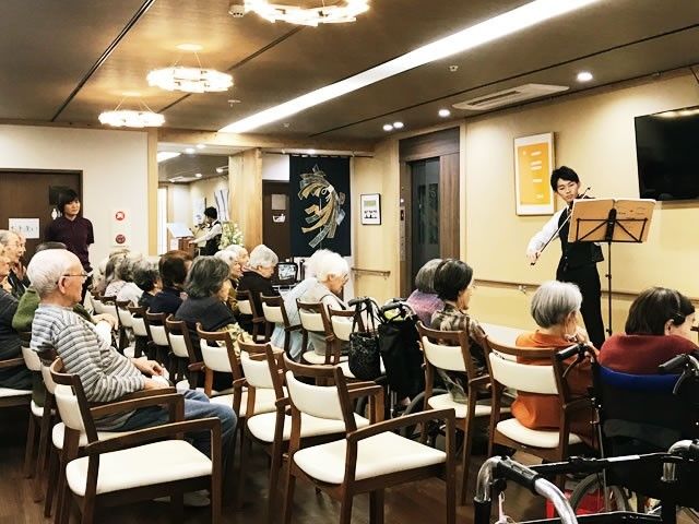 レクリエーションを楽しんでいる様子の高齢者。バイオリン演奏を楽しんでいる様子