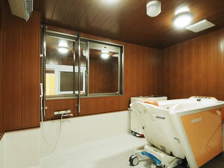 座った姿勢を保てる介護仕様の設備付き浴室。鏡にも手すりの枠が取り付けられている