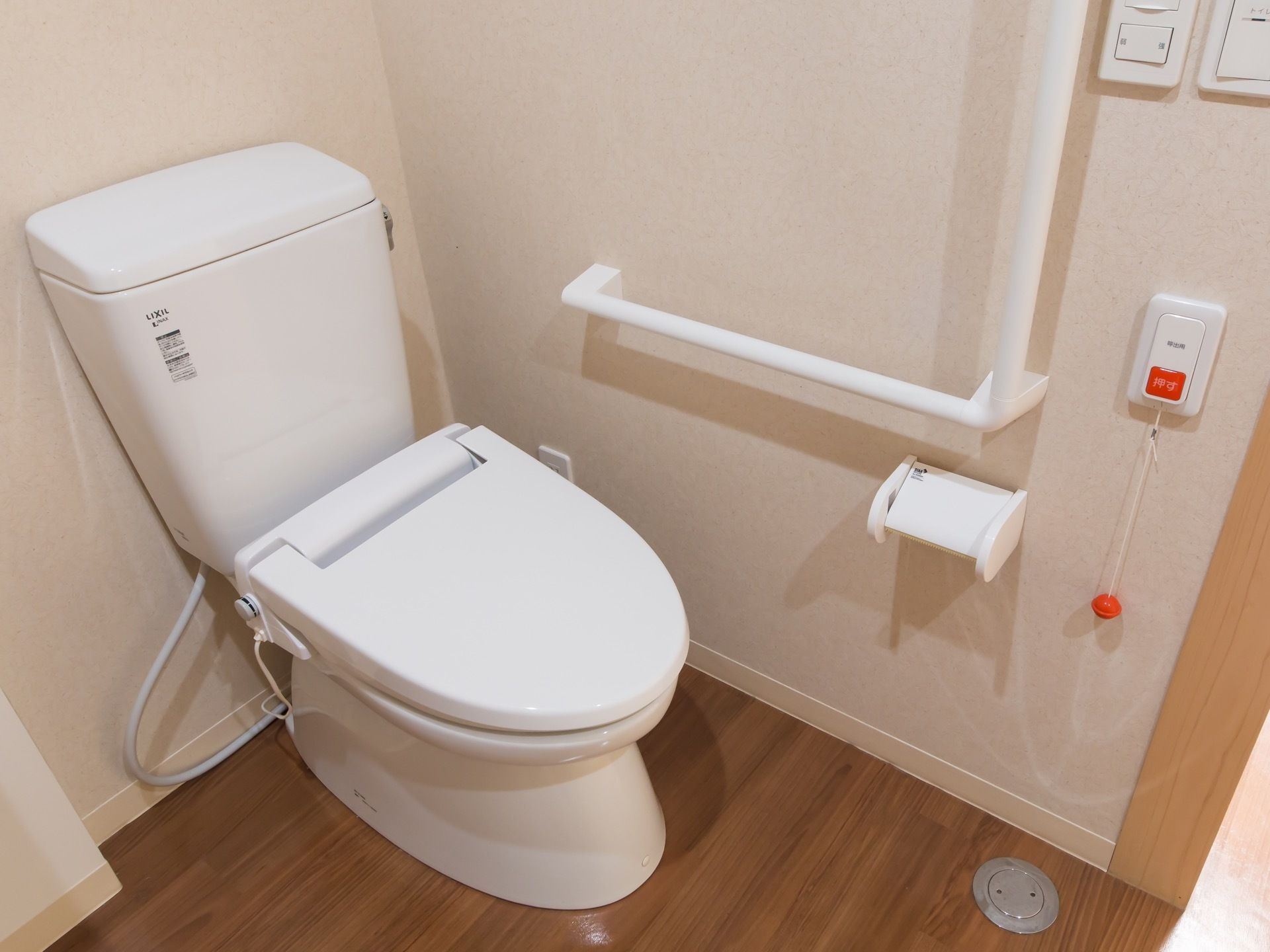 トイレの壁には呼出し用のボタンを設置している。その下側には紐があり、それを引っ張ることにより呼出すことも可能である。