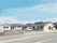 平屋建ての建物はベージュの外壁にグリーンがかった屋根。敷地内には広い駐車場もある。