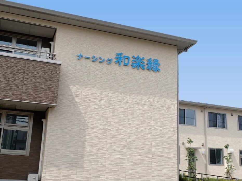 ベージュとブラウンの建物の一部をアップにして映している。外壁にはホーム名がライトブルーの文字で書かれている。