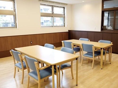 4人掛けのダイニングテーブルセットが複数置かれた食堂。各テーブルにはブルーの椅子がセットされている。