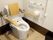 背もたれと手すりが付いたトイレにはオレンジの呼び出しボタンも設置され、広さもある。