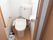 白を基調としたシンプルな温水洗浄機能付きの個室トイレで、壁にはＬ字型の手すりやペーパーホルダーが設置されている。