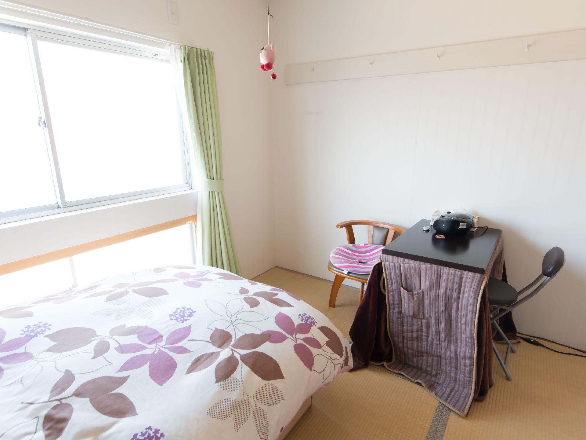 花柄の布団が敷かれたベッドと、保温用の布がまかれたテーブルのある部屋