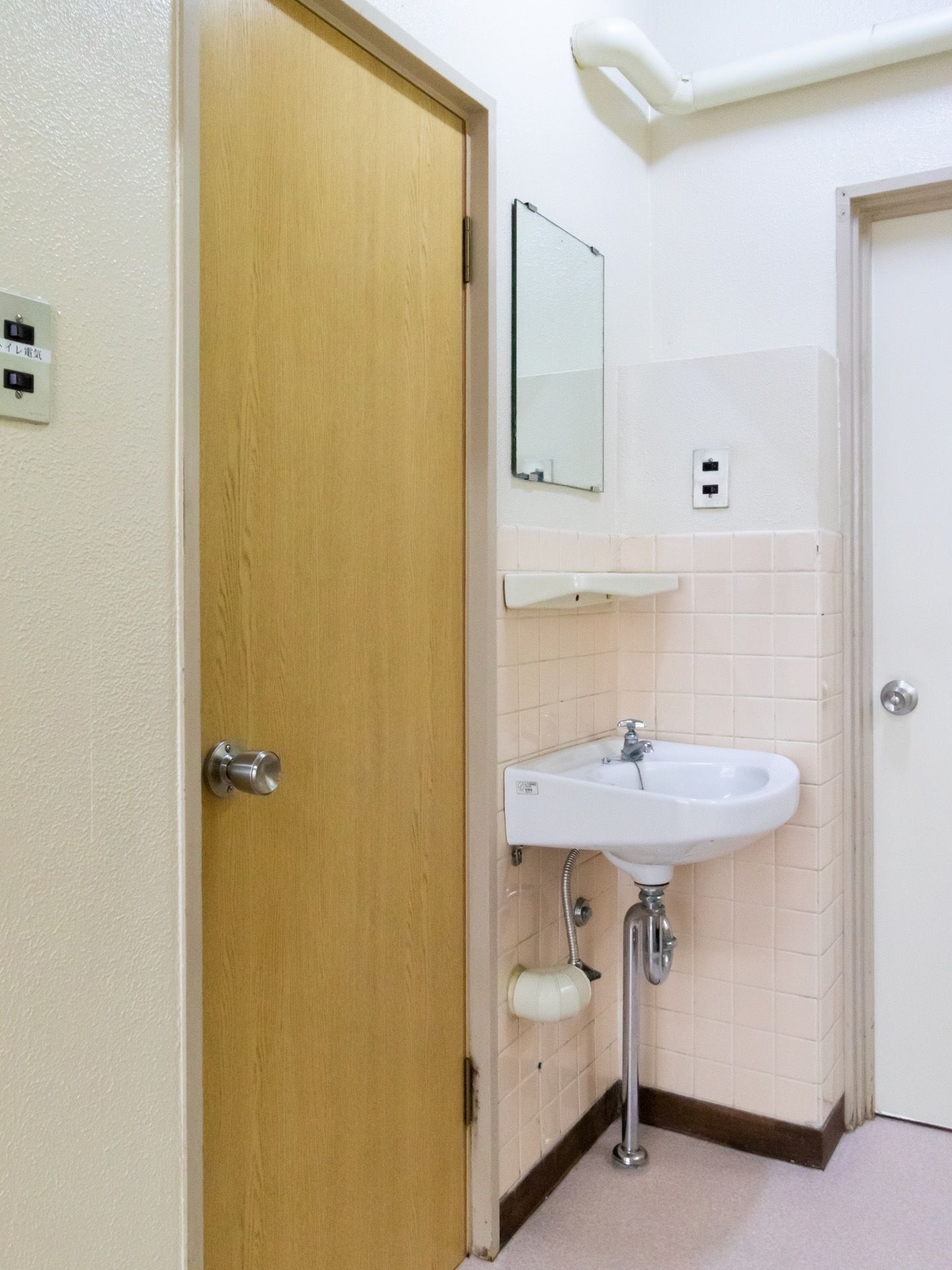 トイレのドア脇に手洗い場が設置されている。洗面ボウルは陶器製で周囲はタイル張りになっており、その上に鏡と棚がしつらえてある。