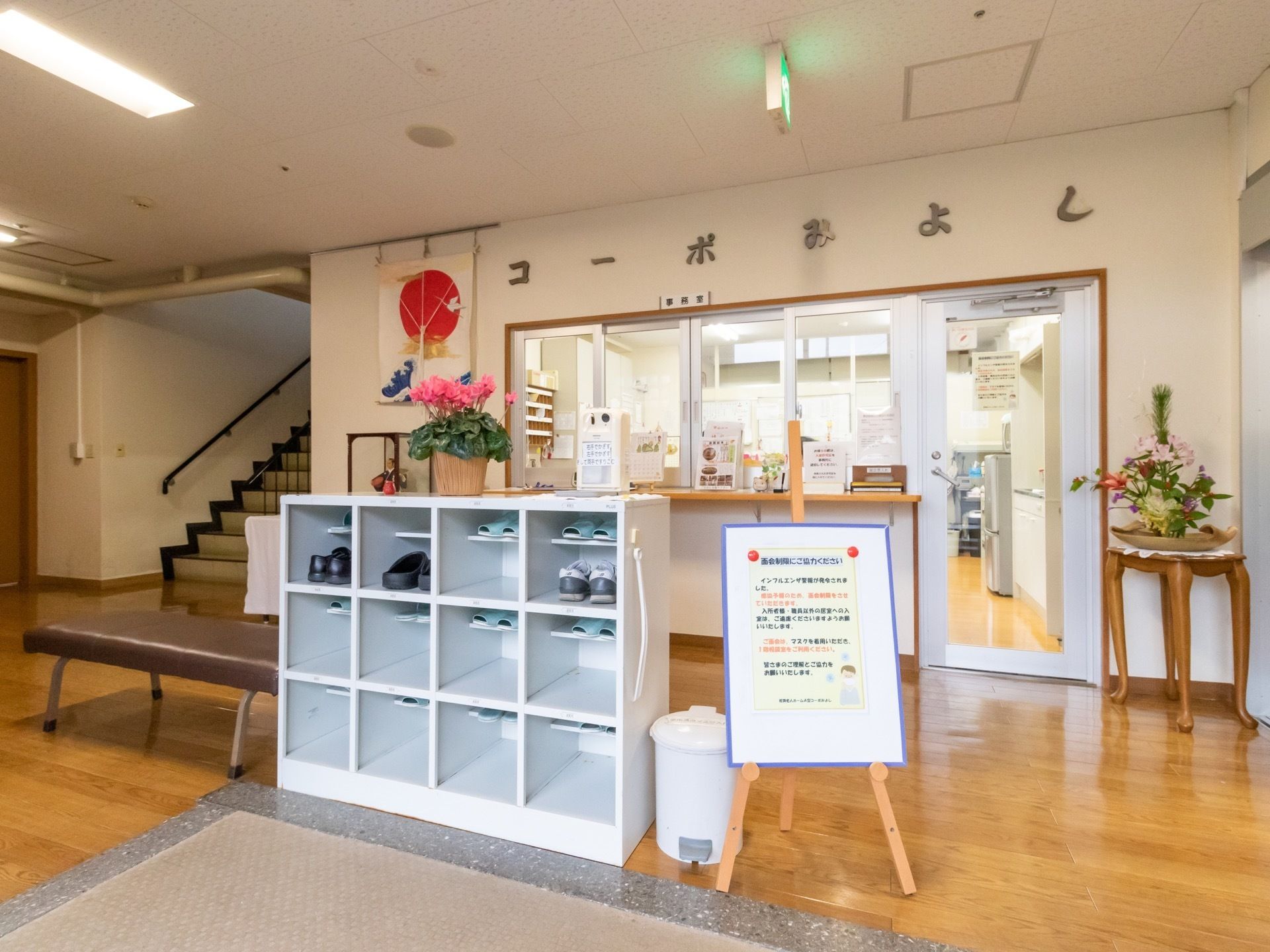 玄関ホールには受付があり、各所に花が飾られている。上がりかまちに来訪者様用の靴箱とベンチが設置されている。