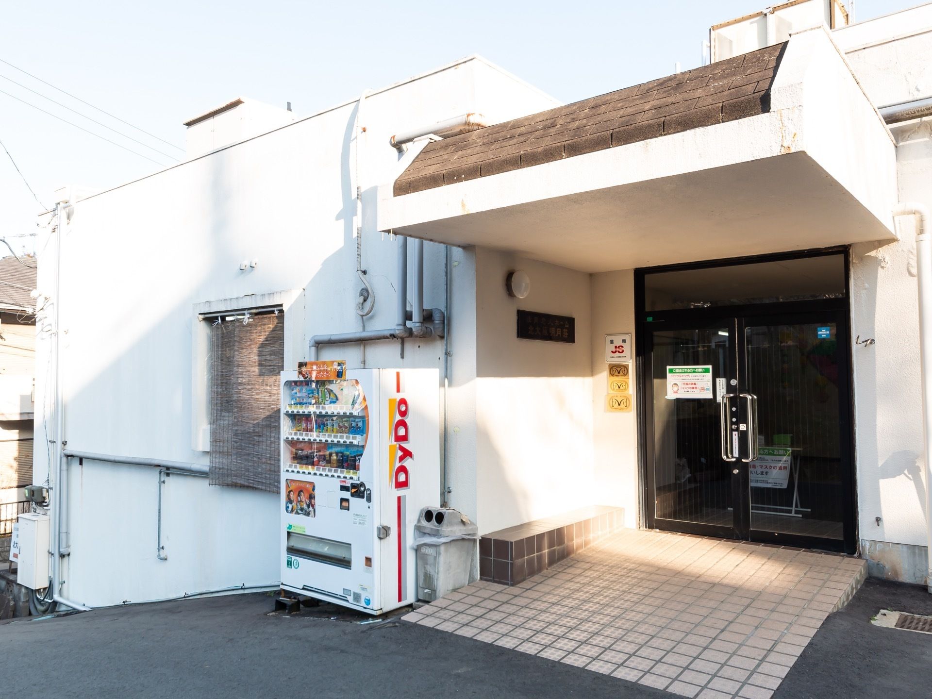 エントランスには、足元がタイル張りでひさし付きの玄関ポーチが設けられている。自販機が設置されている。
