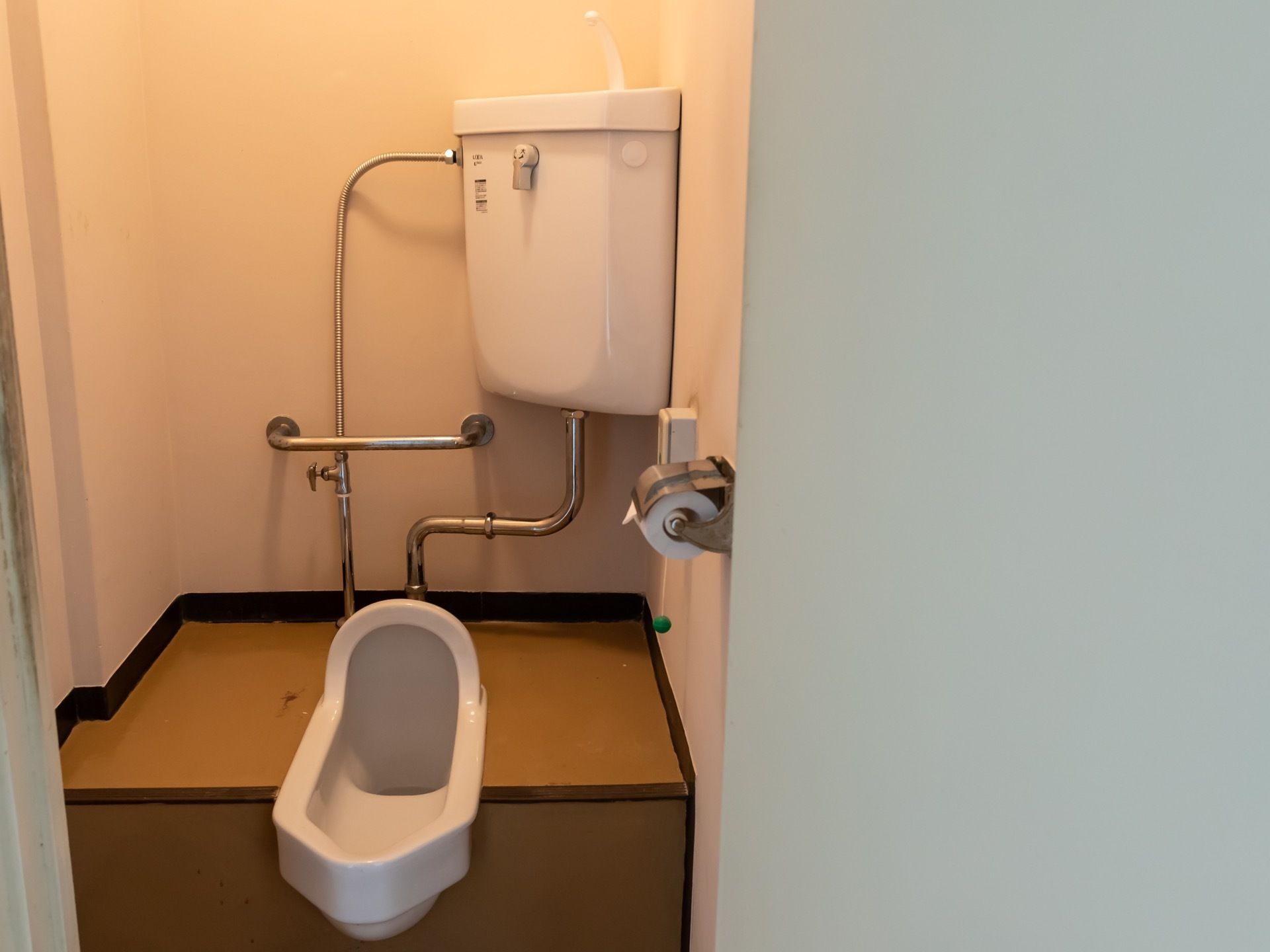 居室には、手洗い付きタンクが備わった和式トイレが完備されている。呼び出しボタンが壁に設置されており、扉は外開きになっている。