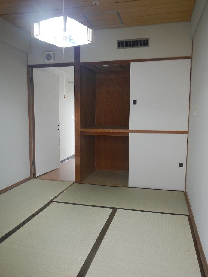 仕切りが付いた押し入れが設置された和室の部屋には畳が敷かれ、奥にはフローリングのフロアと出入り口が見える。