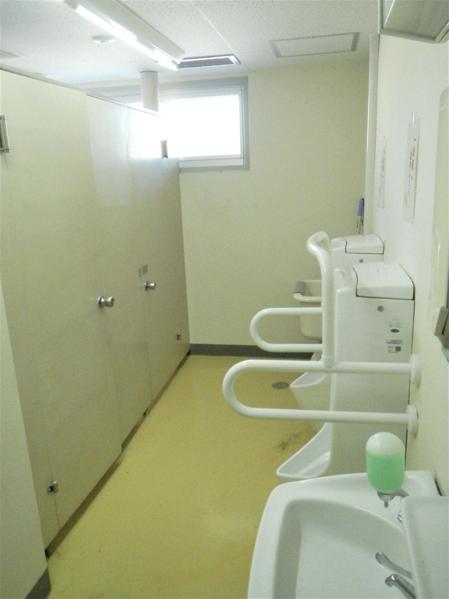 男性用便器の周囲に白い手すりが取り付けられているトイレ
