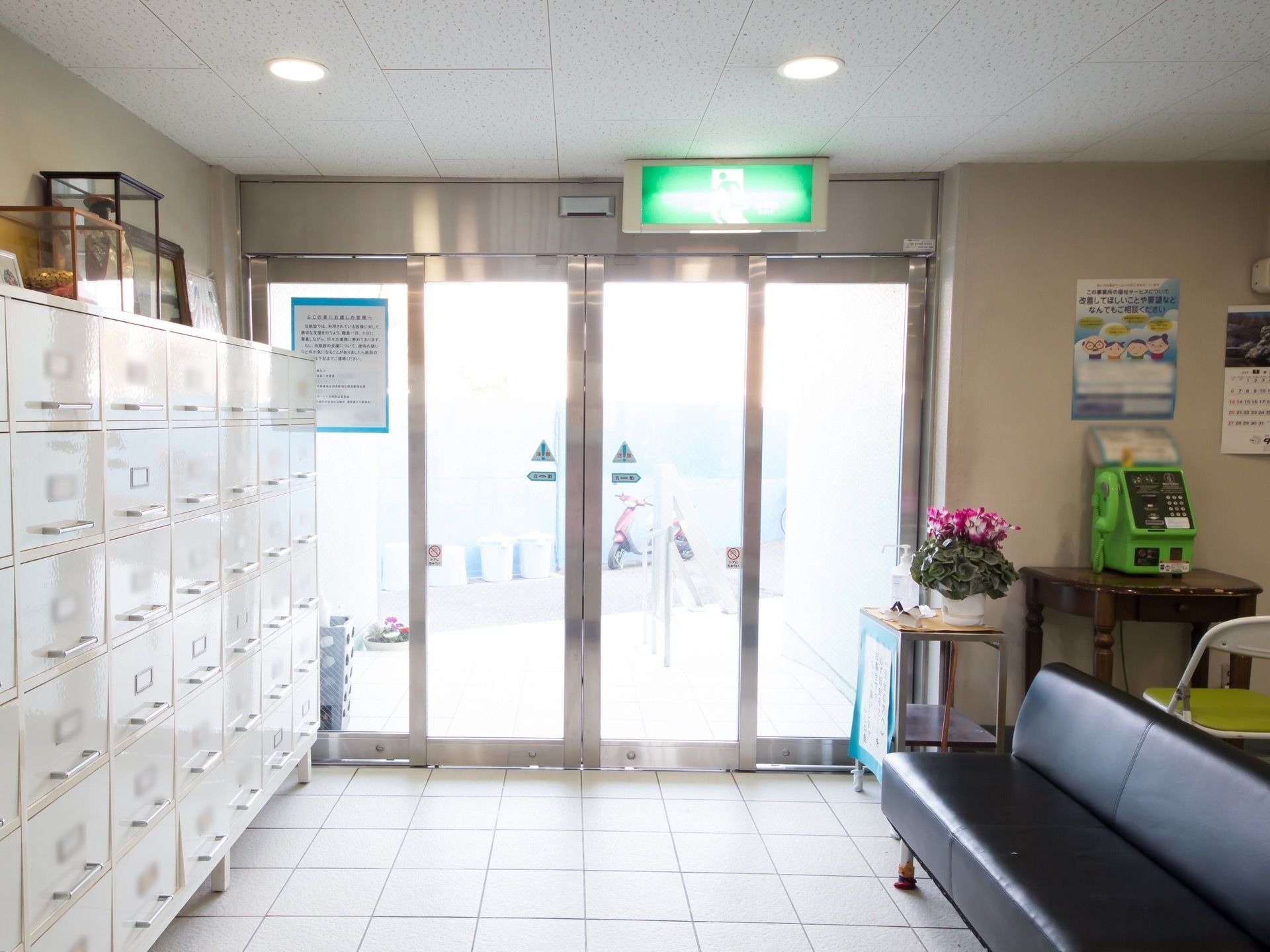 玄関ドアは自動ドアになっている。天井には非常口の指示看板が設置されている。入口横には下駄箱が用意されている。