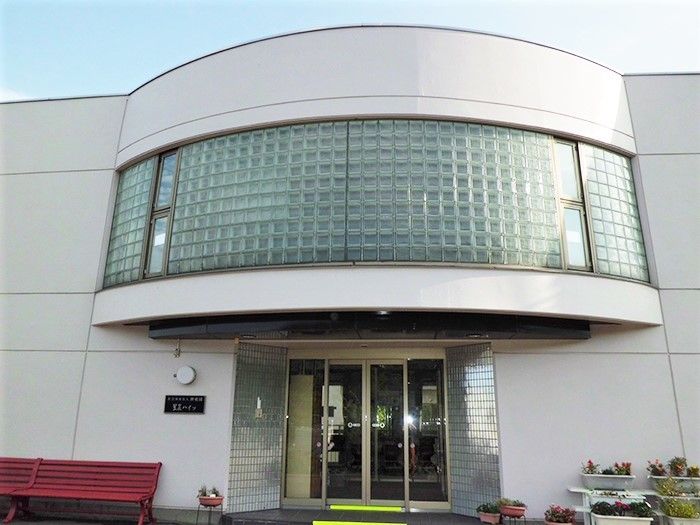 玄関の上の部分には半円型の屋根が付き、大きな窓も付いている。玄関は自動ドアで近くにベンチやプランターがある。