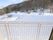 白いフェンスが設置されたバルコニーから、雪景色が望める環境にある。葉の落ちた木や枯れかかった草は、雪に覆われている。