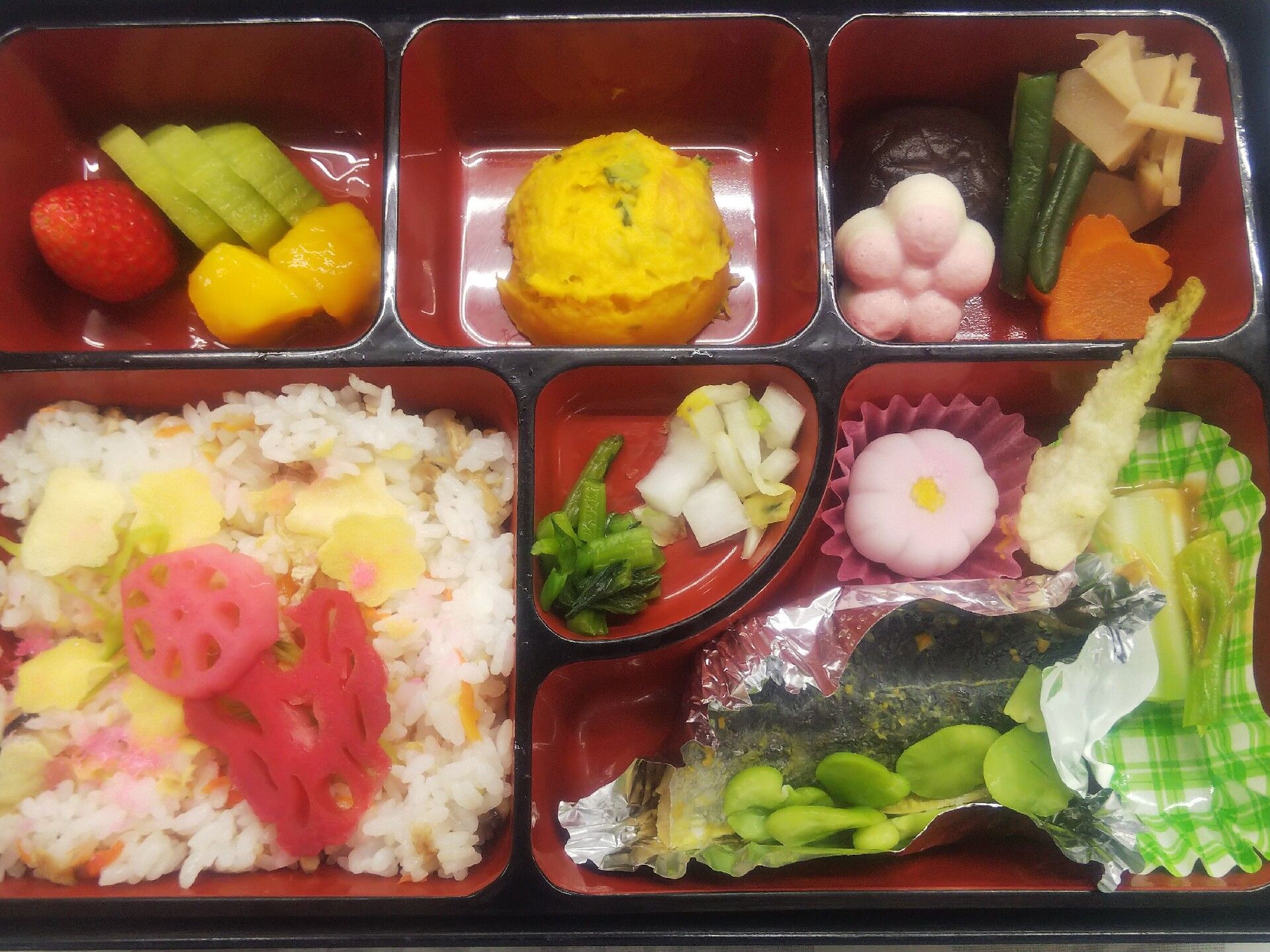 ピンクに染められた酢レンコンが飾られたちらし寿司やそら豆が添えられた魚、煮物や漬物が詰められた弁当。