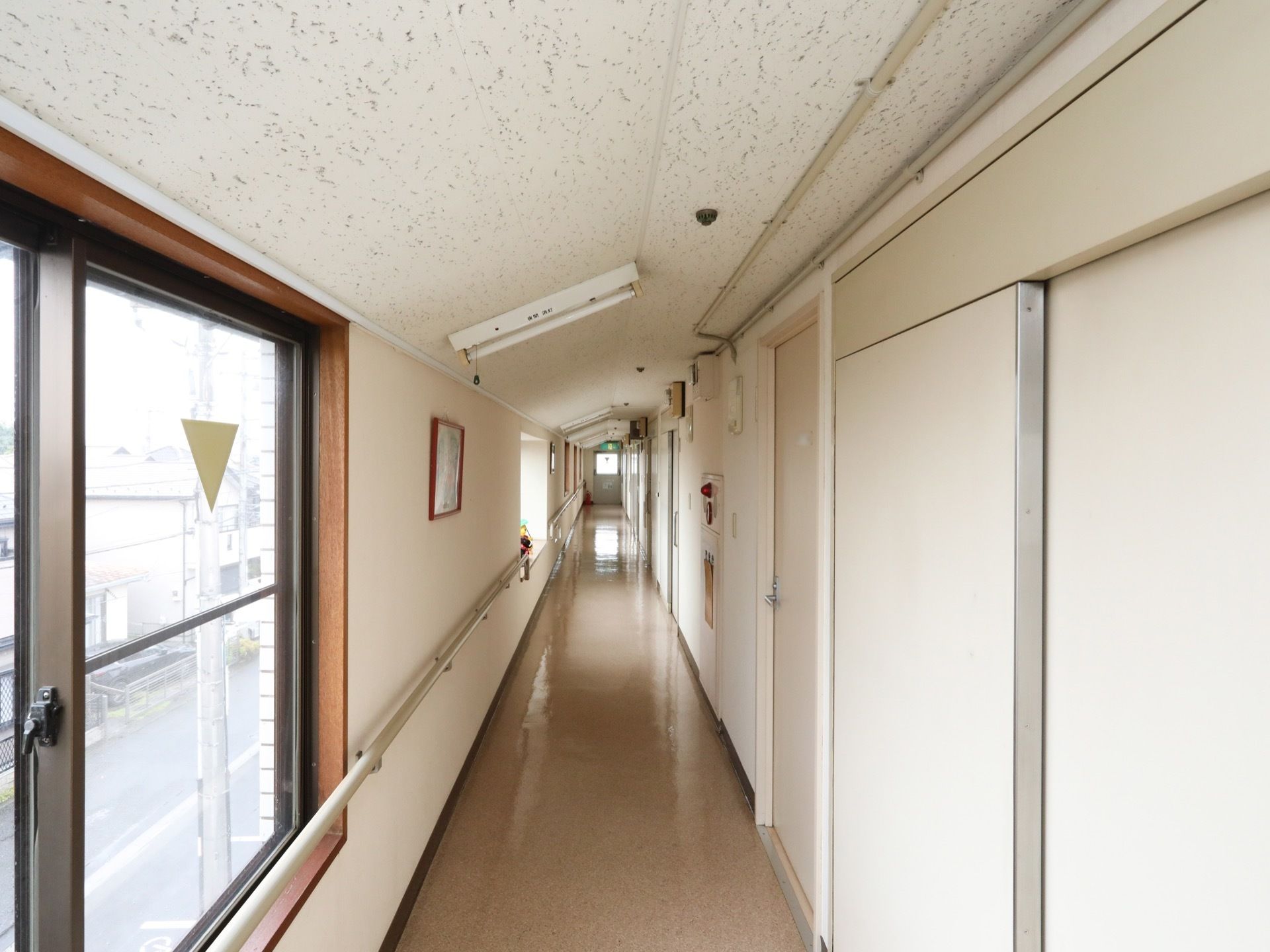 屋根に近い最上階の廊下は、天井の一部が斜めになっている。窓がある方の壁に、長い手すりがかかっている。