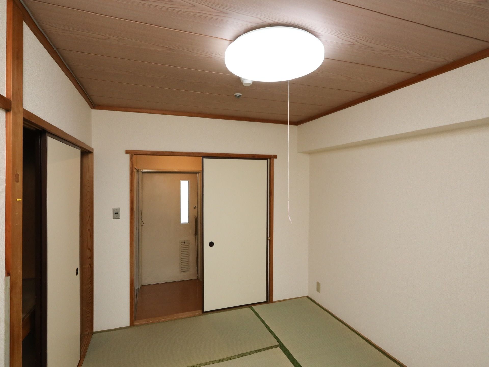 白壁に、天井は木目調を採用した和室である。出入口から右側に押入れがあり、収納スペースも充実している。