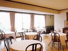 丸いテーブルには手-ブルクロスがかけられ、大きな窓にはピンクのカーテンが付いている。