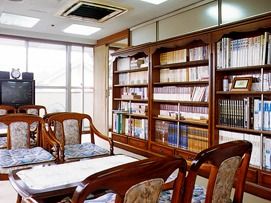大きな窓が付いた部屋にはたくさんの本が並んだ大きな本棚やテレビ、応接セットが置かれている。