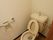 木製の引き戸で仕切られたスペースに洋式便器が据えてある。壁面にはトイレットペーパーホルダーとステンレス製の手すりがある。