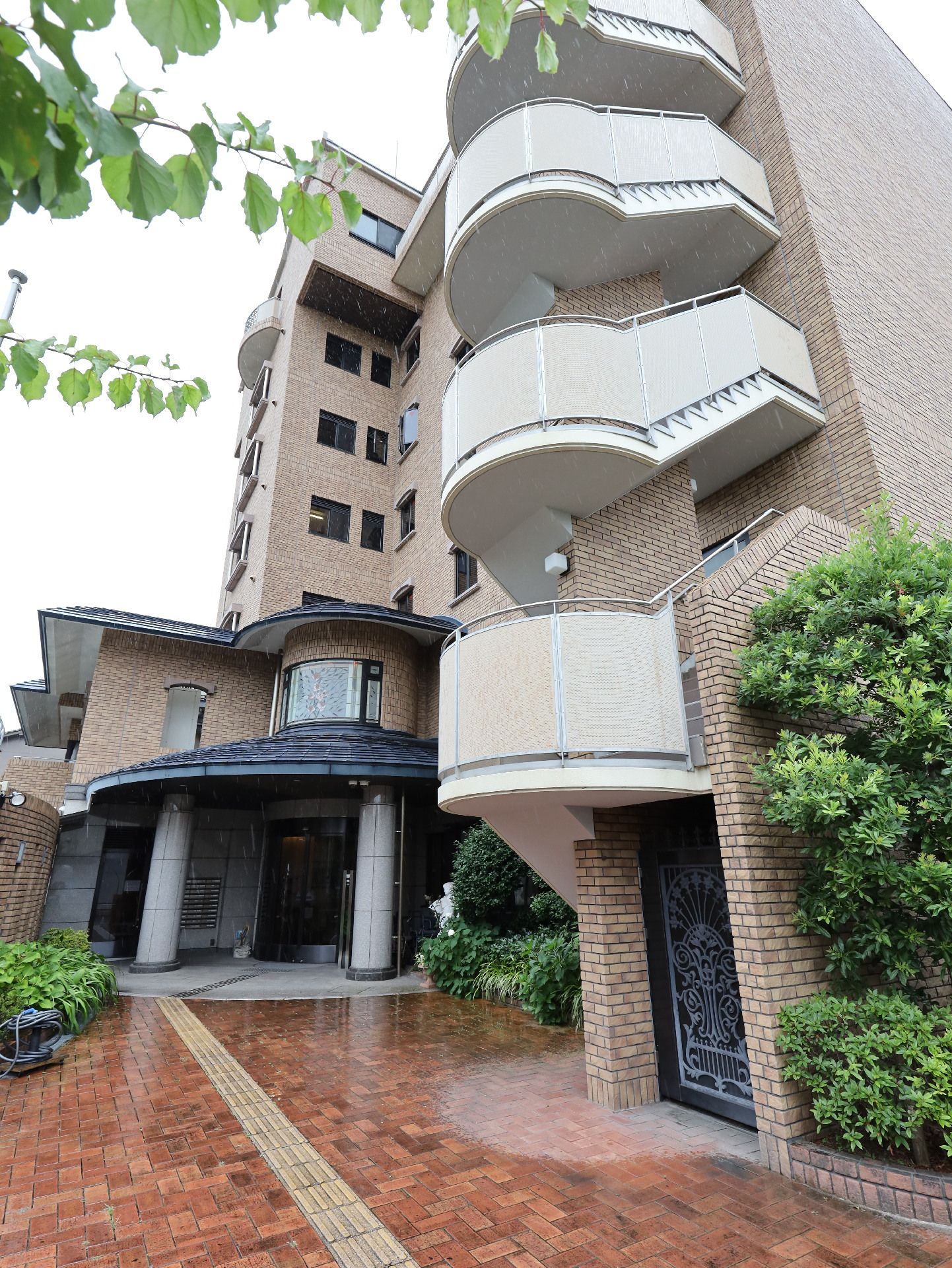 赤いレンガ調の通路の先にあるレンガ調の６階建ての建物