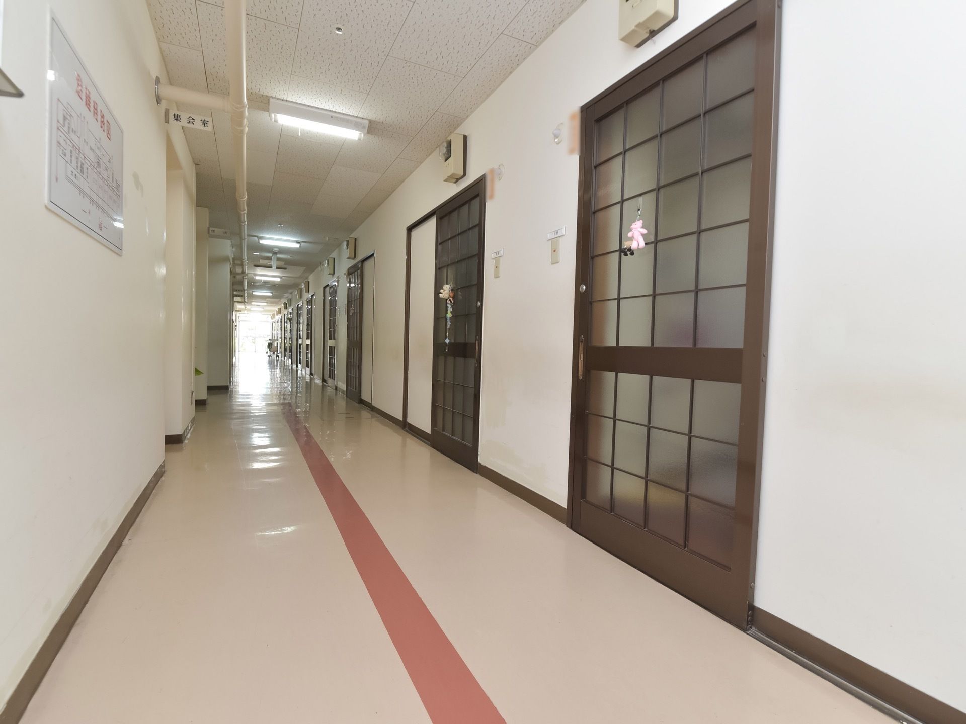 白を基調とした明るい廊下である。通行しやすいようセンターラインが引かれている。居室ドアは間口の広い引き戸である。