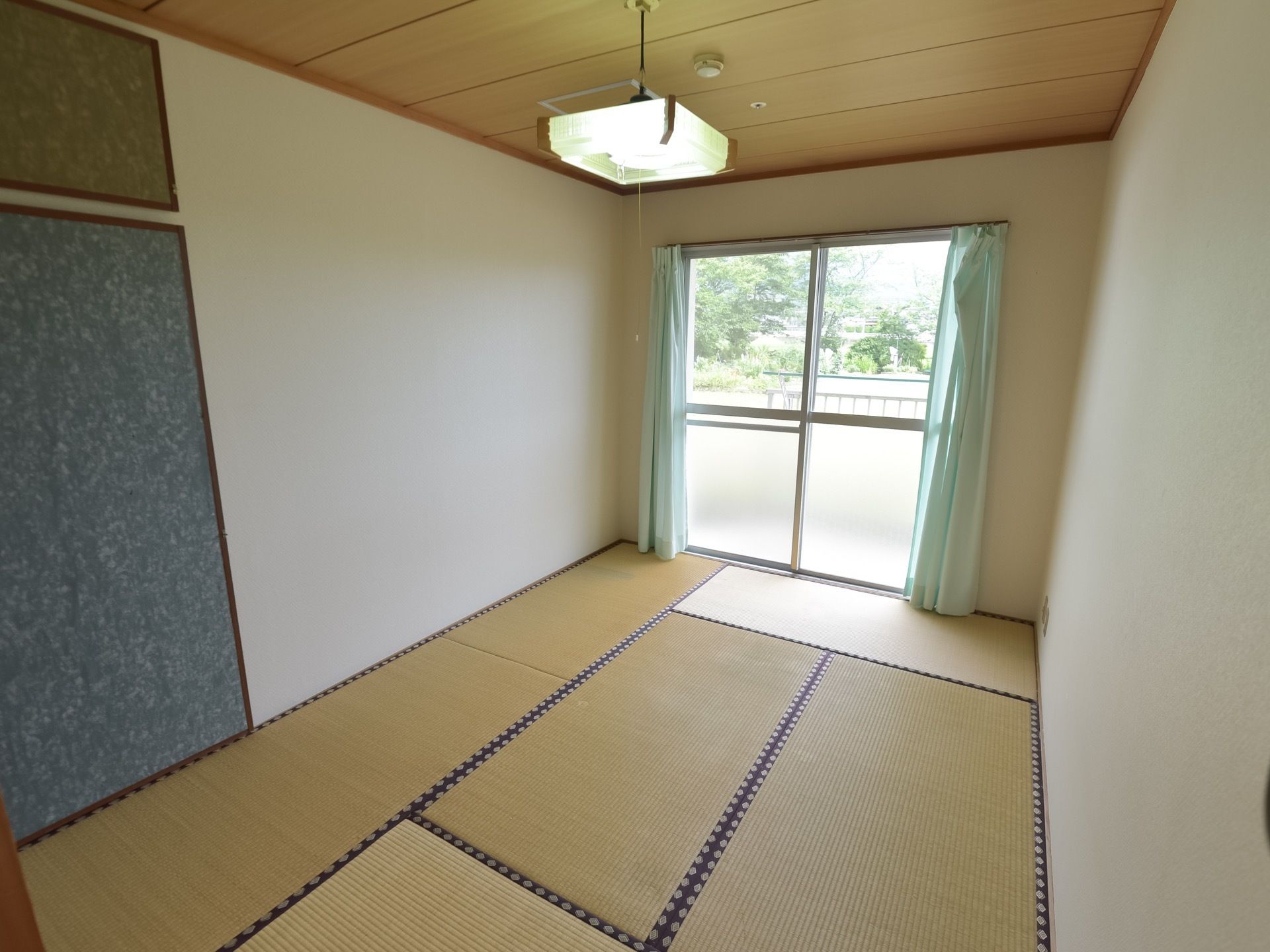 居室は六畳の和室である。和風の照明器具やカーテンが完備されている。大きな窓からは美しい庭が堪能できる。
