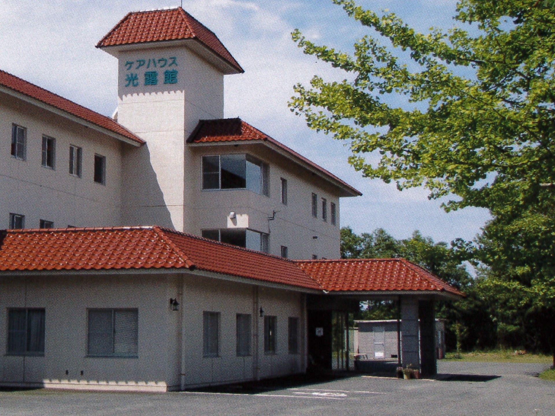茶色い瓦屋根が付いた３階建ての建物。白い外壁にはハウス名が書かれている。