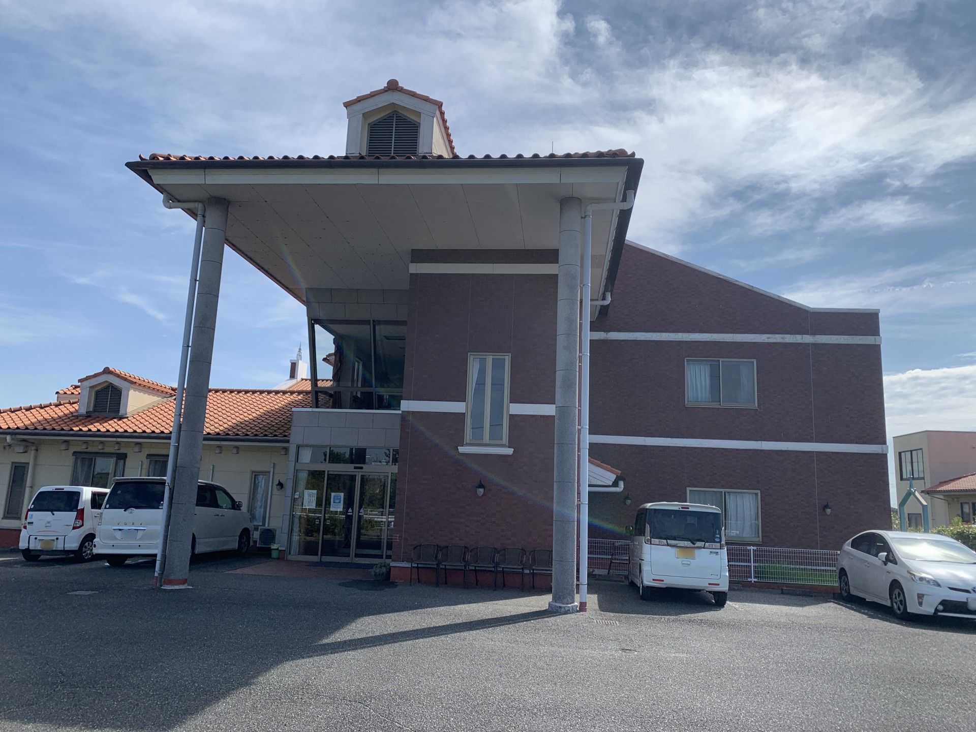 なにかを指さして笑顔で話している車いすの女性とそれを押している介護スタッフの様子