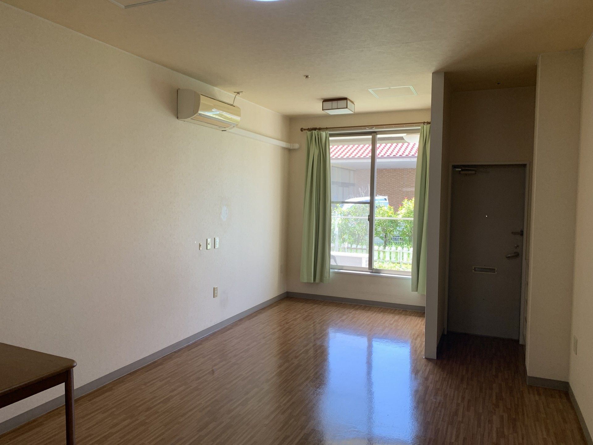 自然が広がる場所で車いすに乗りリラックスする女性とスタッフ。カメラに笑顔を向けている様子