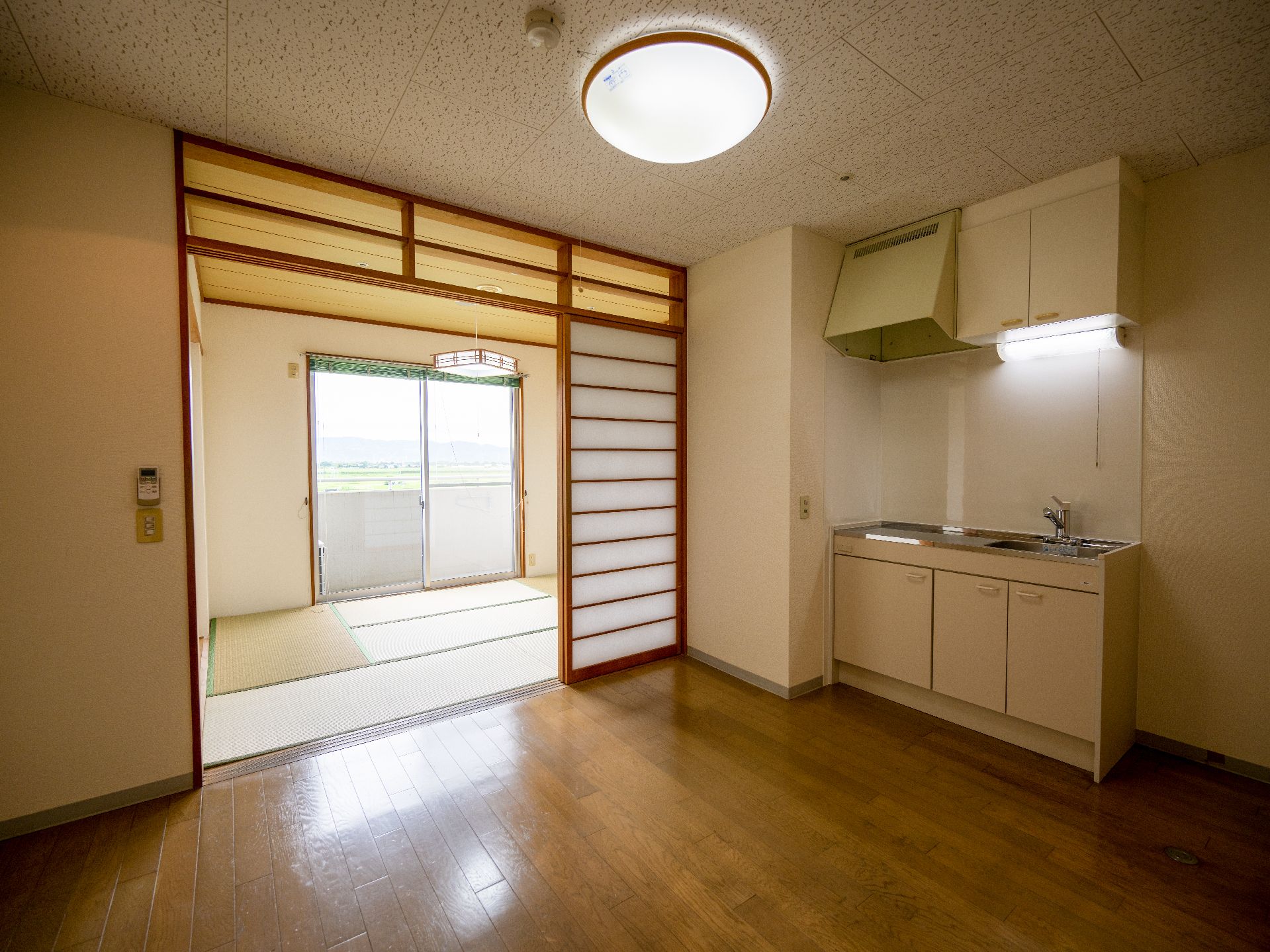 フローリングの床の部屋の一角に設けられた白いミニキッチン