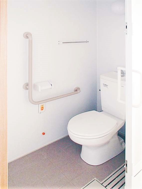 エル字型の手すりが設置されたトイレには呼び出しボタンもついている。ドアは引き戸。