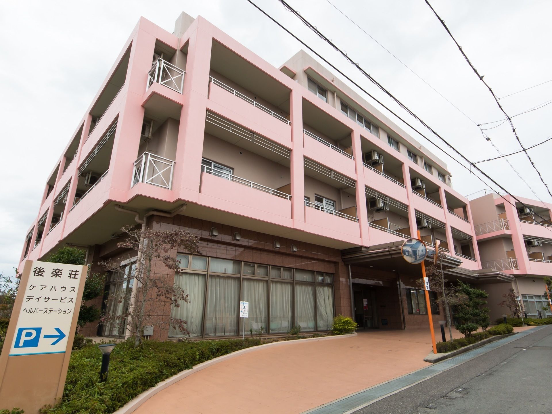 ピンク色の柔らかい印象の住宅がある。玄関前はロータリーになっていて、車寄せができるようになっている。