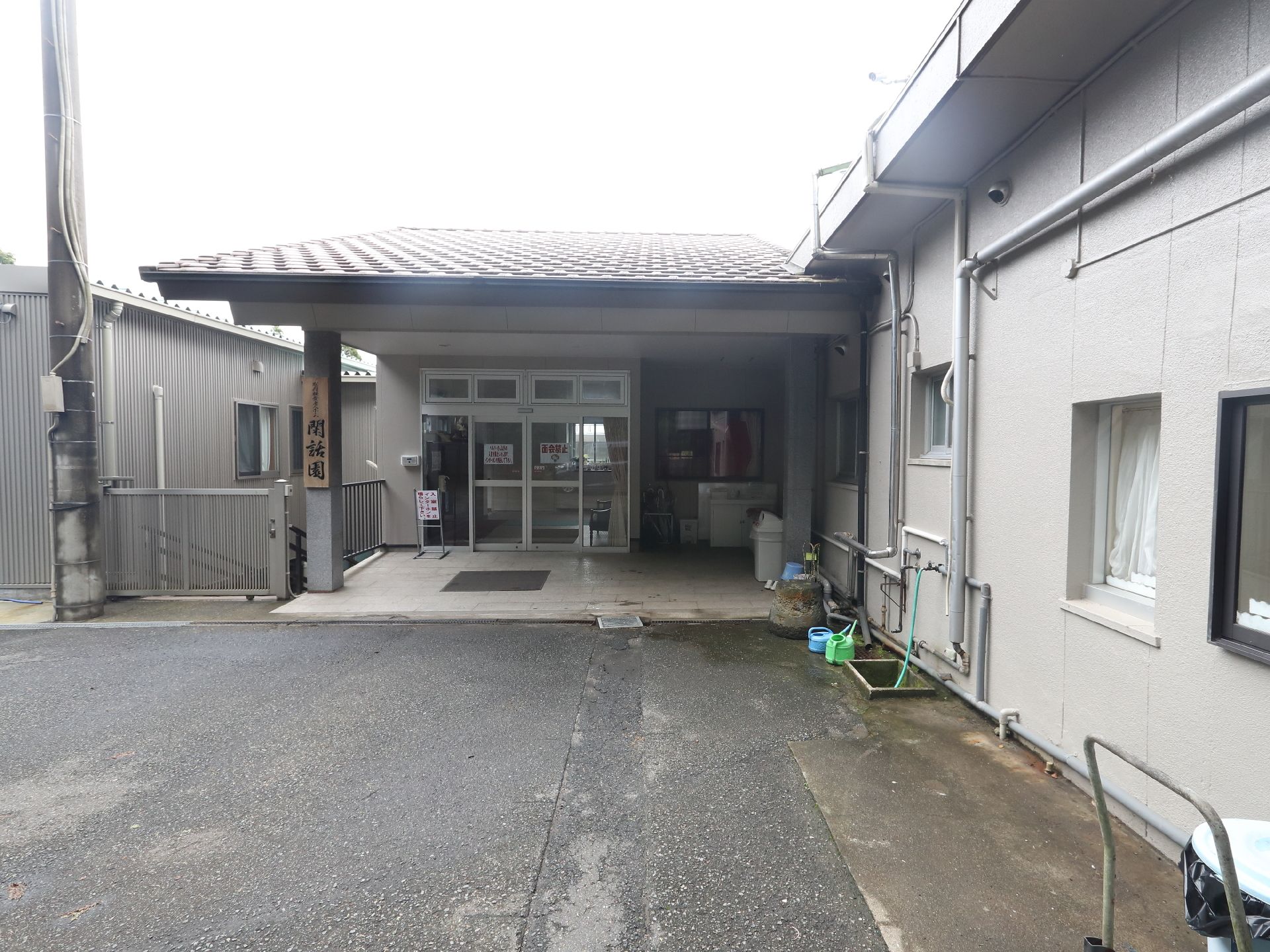 日当たりのいい室内で笑顔でアジサイの貼り絵をしている高齢女性とエプロンを付けた若い女性スタッフ。