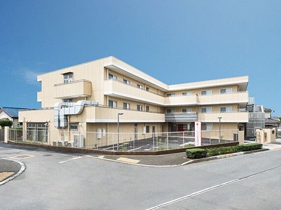 3階建ての建物はエル字型で各フロアにベランダがあり、敷地内には駐車場が付いている。